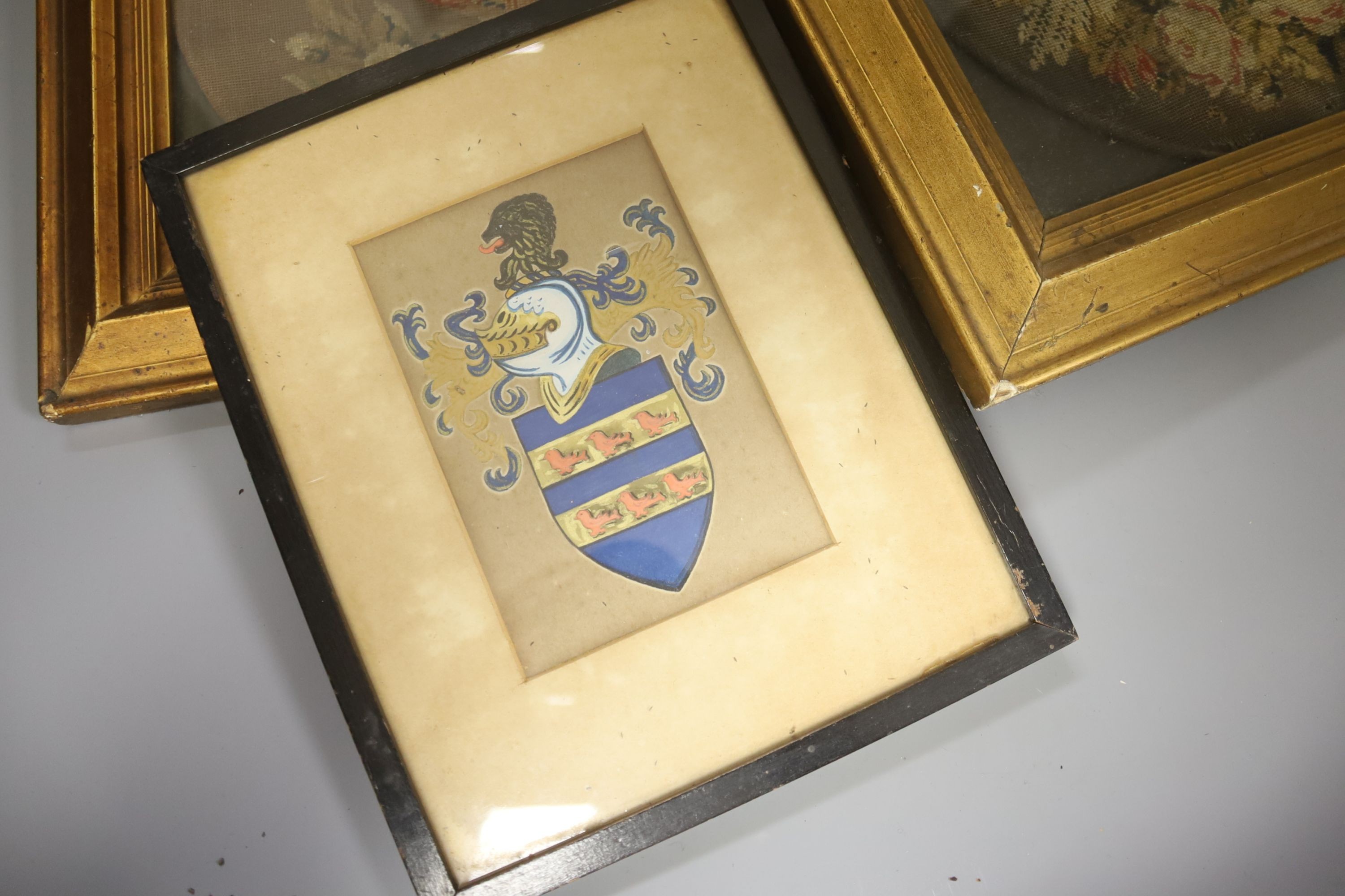 Pair of 19th century petit point face screens, a 1920s sampler and a heraldic panel, all framed.